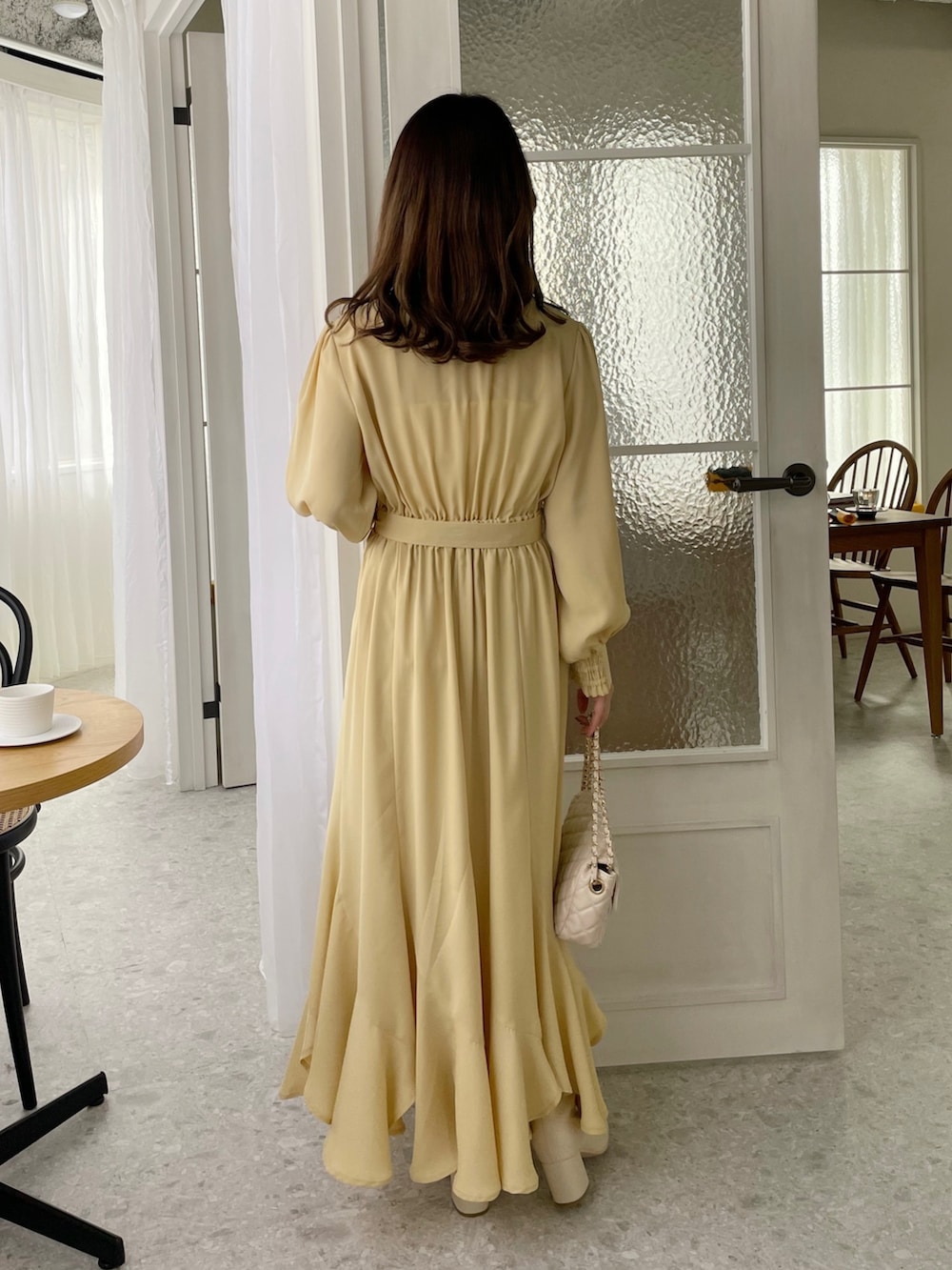 イエロー系のワンピース、ホワイト系のバッグ、ホワイト系のブーツを着用したレディースの冬コーディネートの2枚目の写真