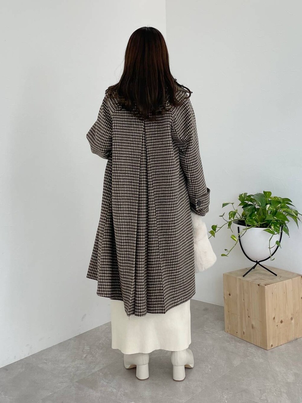 ホワイト系のブーツ、ホワイト系のハンドバッグ、ブラウン系のチェスターコートを着用したレディースの秋コーディネートの3枚目の写真