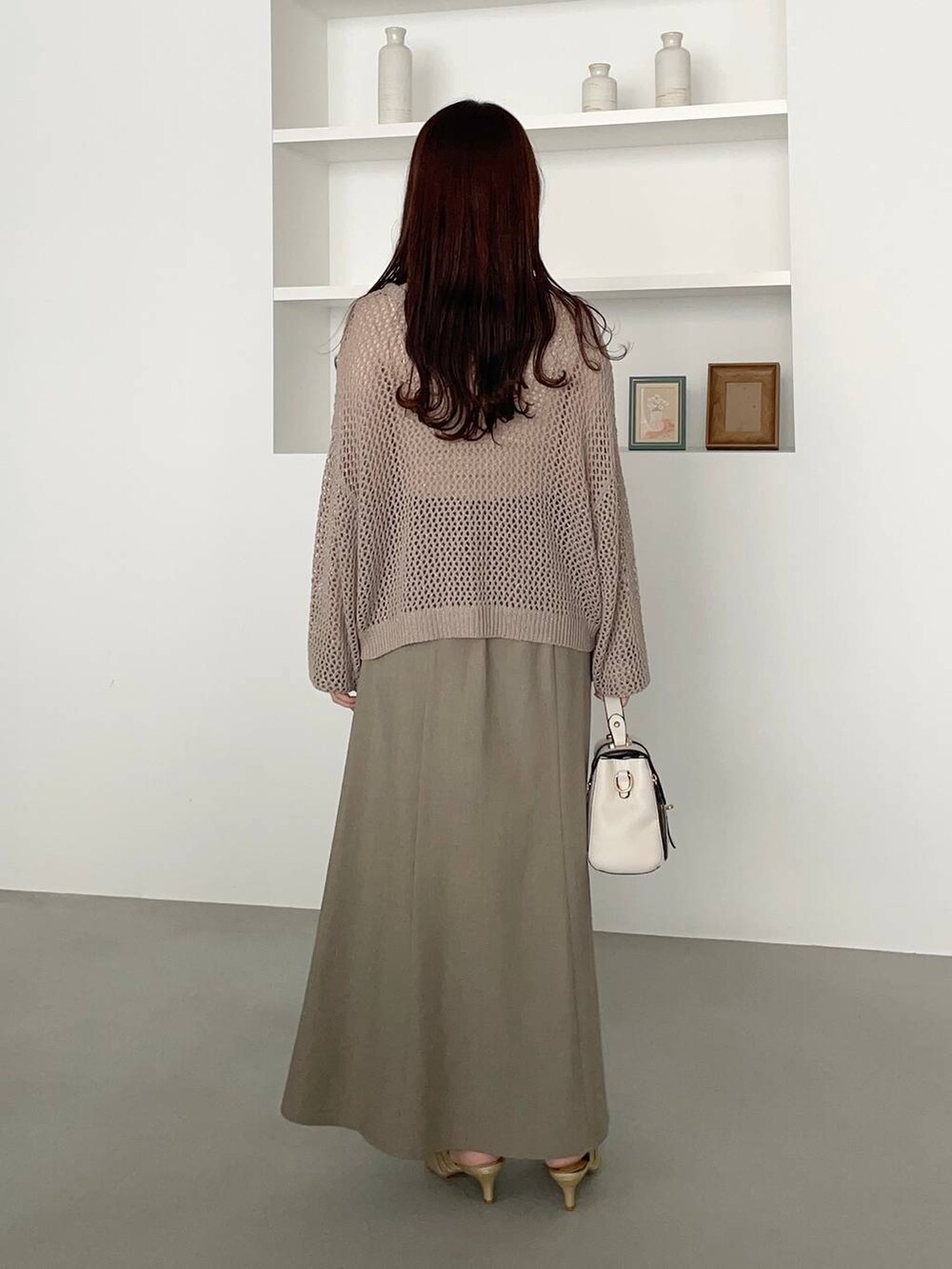 ゴールド系のパンプス、ホワイト系のショルダーバッグ、ベージュ系のニット/セーターを着用したレディースの夏コーディネートの2枚目の写真