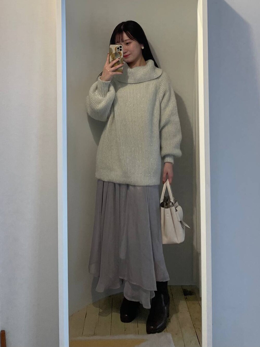 ブラウン系のブーツ、ブルー系のスカート、ホワイト系のショルダーバッグを着用したレディースの冬コーディネートの4枚目の写真