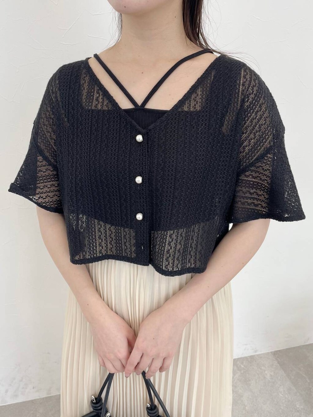 ブラック系のバレエシューズ、ブラック系のカーディガン/ボレロ、ホワイト系のスカートを着用したレディースの春コーディネートの3枚目の写真