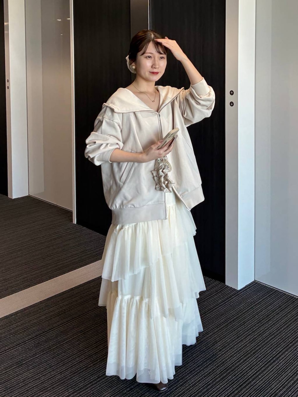 ホワイト系のパーカー、ホワイト系のスカート、ホワイト系のスマホグッズを着用したレディースの冬コーディネートの3枚目の写真