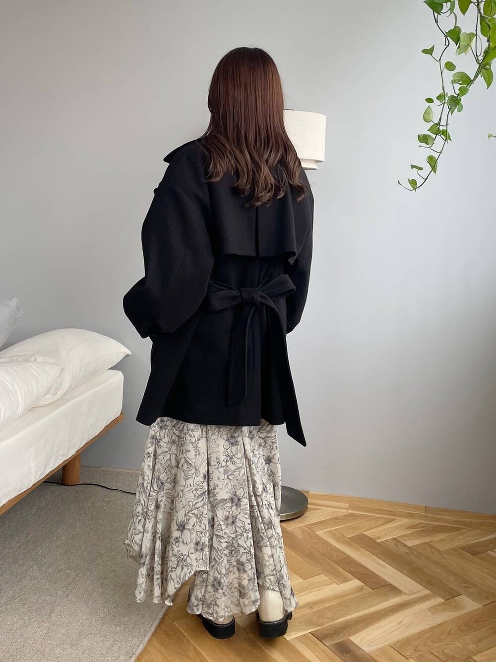 ブラック系のチェスターコート、ホワイト系のブーツ、ベージュ系のスカートを着用したレディースの秋コーディネートの2枚目の写真