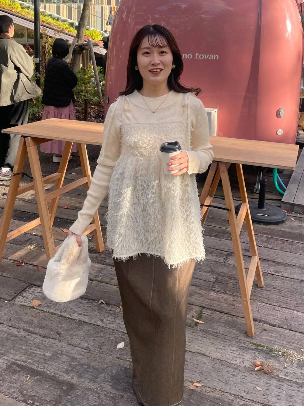 ホワイト系のニット/セーター、ホワイト系のハンドバッグ、ブラウン系のスカートを着用したレディースの冬コーディネートの2枚目の写真