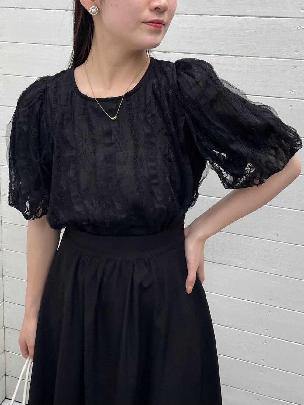 ホワイト系のハンドバッグ、ホワイト系のサンダル、ブラック系のシャツ/ブラウスを着用したレディースの夏コーディネートの3枚目の写真