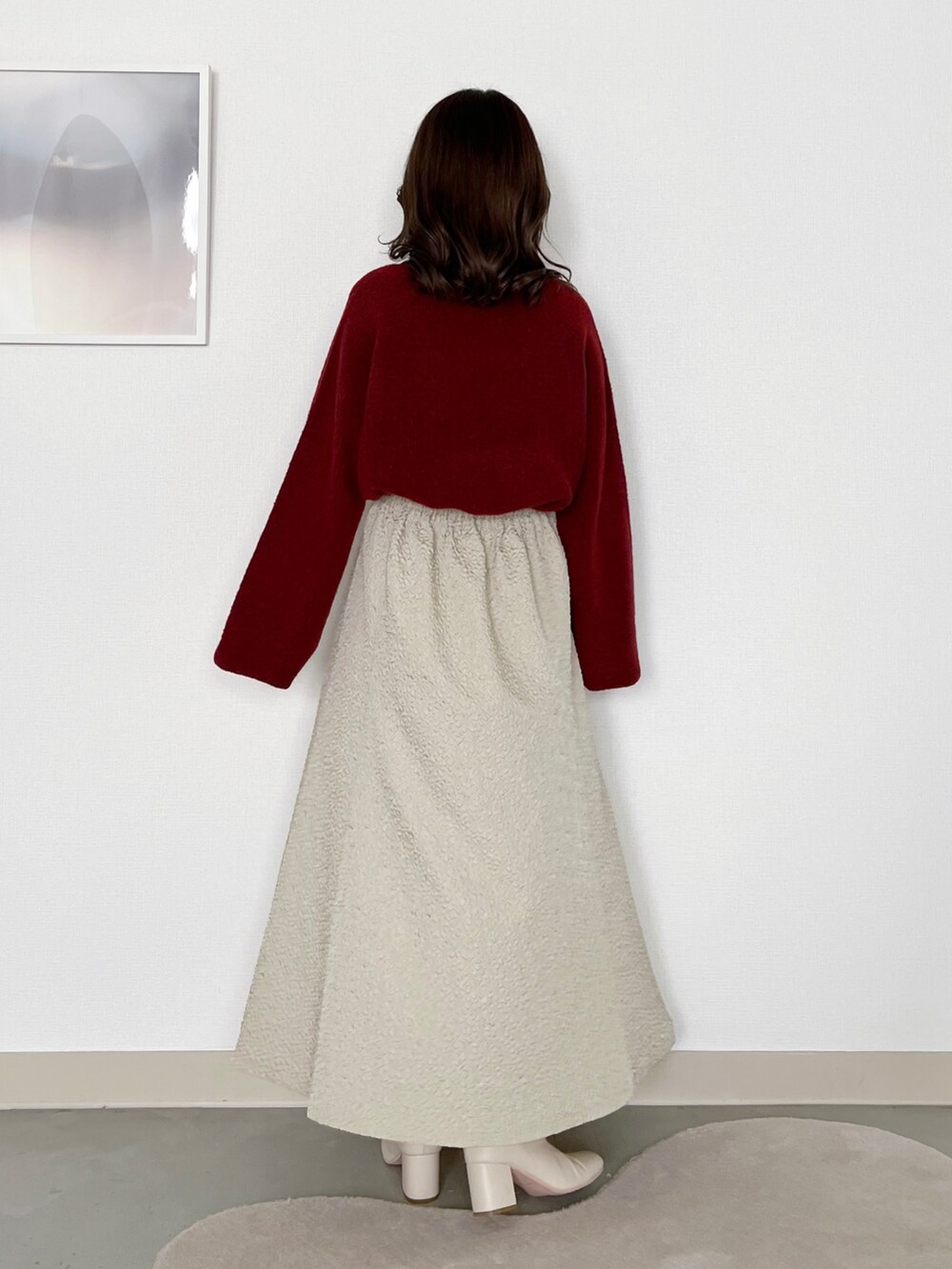 レッド系のニット/セーター、ホワイト系のブルゾン、ホワイト系のスカートを着用したレディースの冬コーディネートの4枚目の写真