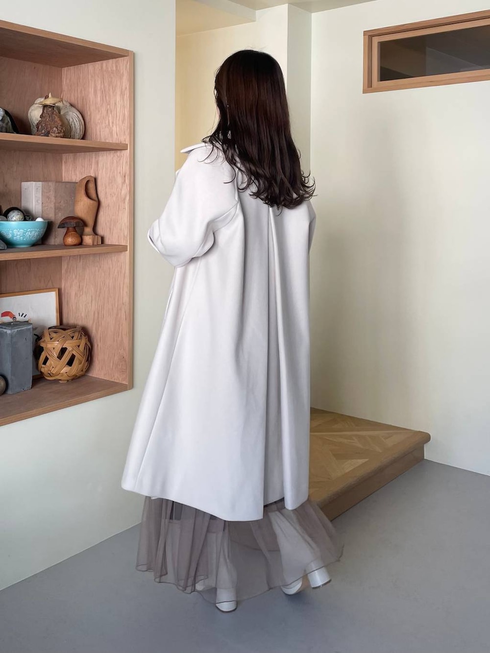 ホワイト系のチェスターコート、ホワイト系のブーツ、ホワイト系のショルダーバッグを着用したレディースの冬コーディネートの2枚目の写真