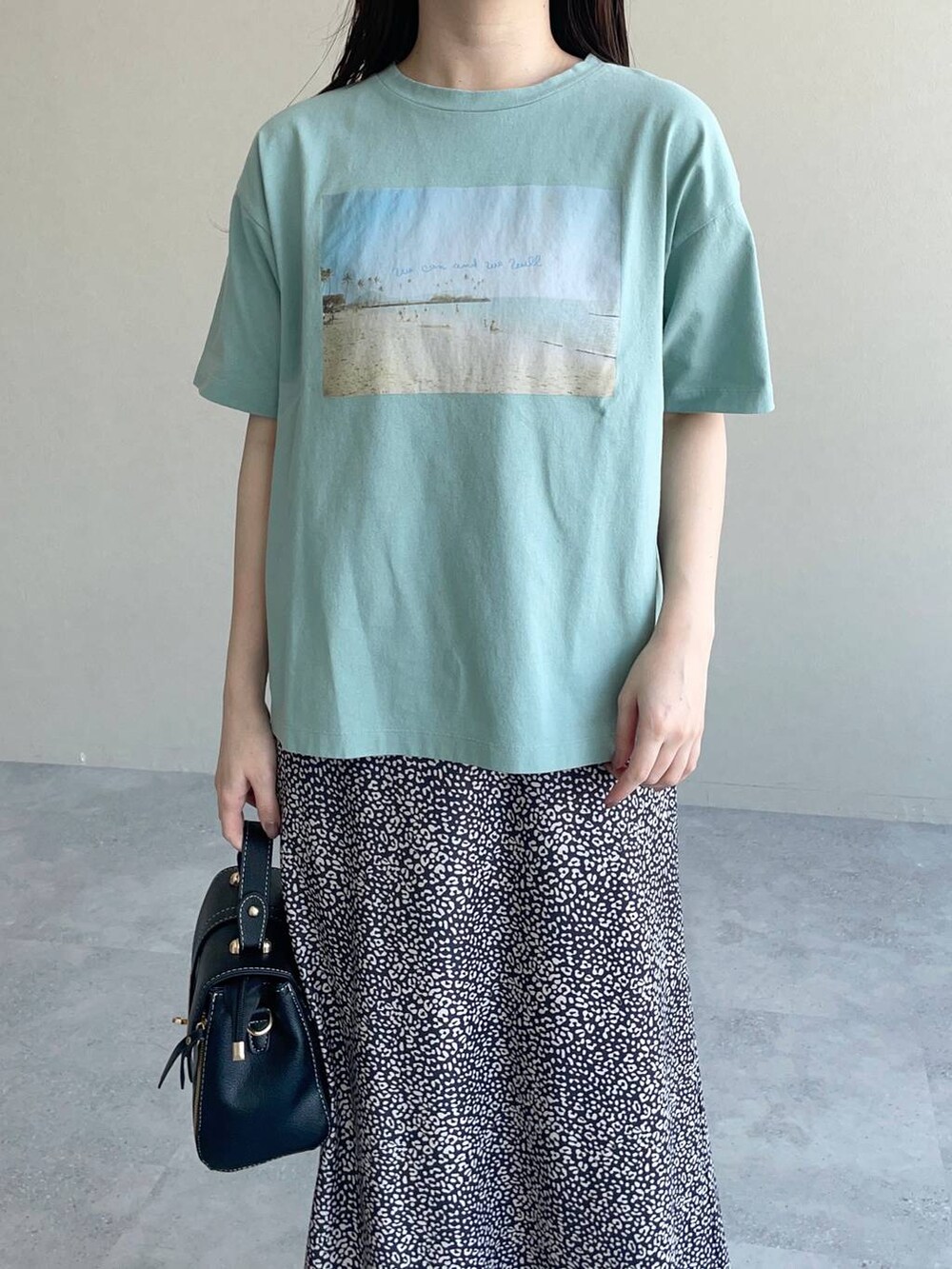 ブラック系のスカート、ブラック系のパンプス、グリーン系のTシャツ/カットソーを着用したレディースの春コーディネートの3枚目の写真