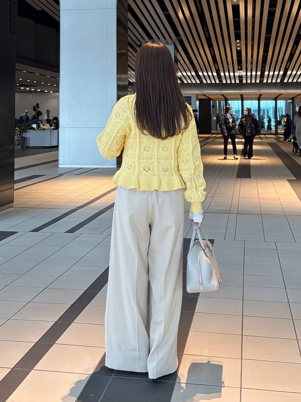 ホワイト系のTシャツ/カットソー、ベージュ系のハンドバッグ、イエロー系のカーディガン/ボレロを着用したレディースの冬コーディネートの2枚目の写真