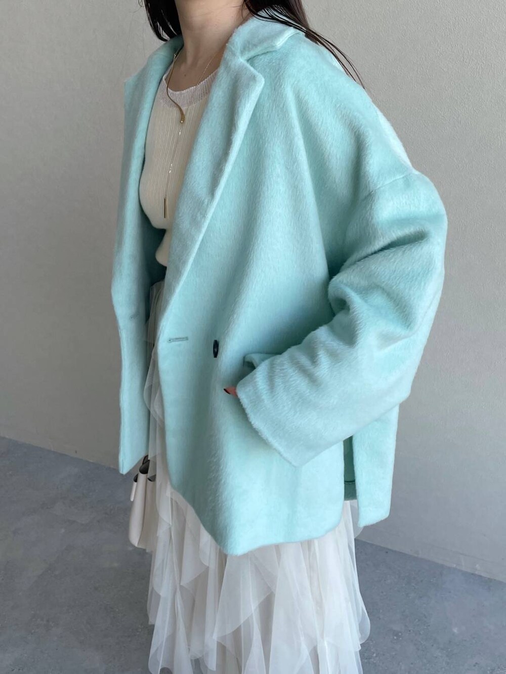 ホワイト系のブーツ、ホワイト系のショルダーバッグ、グリーン系のテーラードジャケットを着用したレディースの冬コーディネートの4枚目の写真