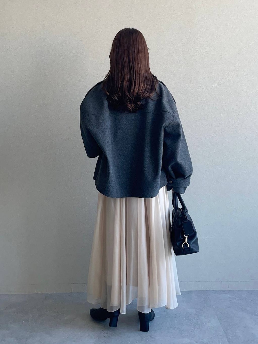 グレー系のピーコート、ホワイト系のニット/セーター、ブラック系のボストンバッグを着用したレディースの冬コーディネートの2枚目の写真