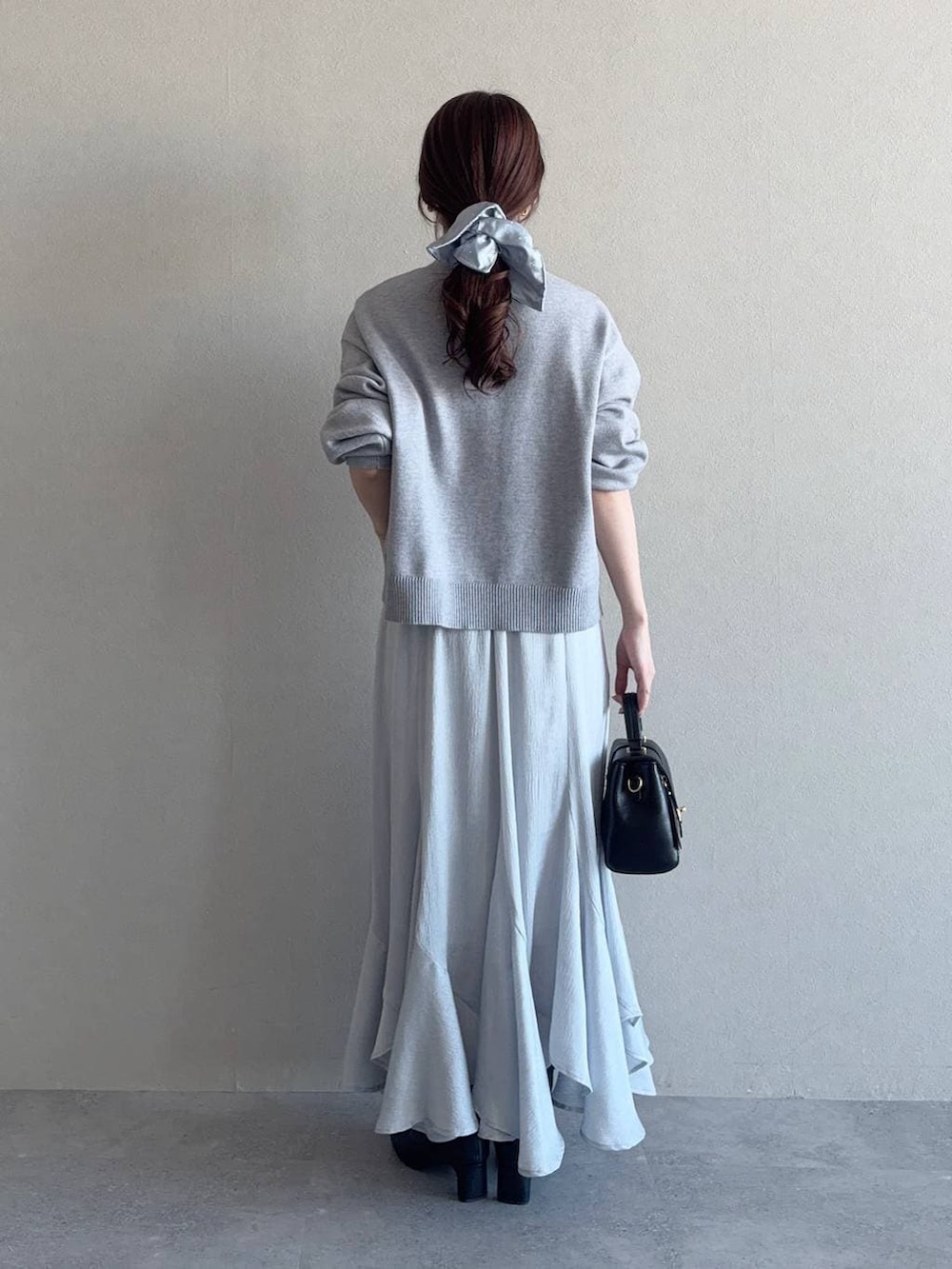 ブラック系のブーツ、ブラック系のショルダーバッグ、ブルー系のスカートを着用したレディースの冬コーディネートの2枚目の写真