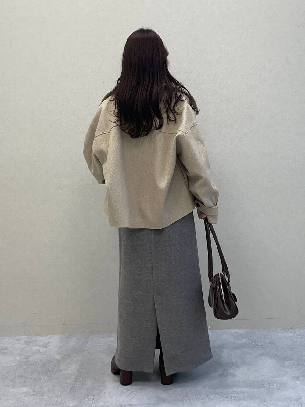 ベージュ系のピーコート、ブラウン系のブーツ、グレー系のワンピースを着用したレディースの秋コーディネートの2枚目の写真