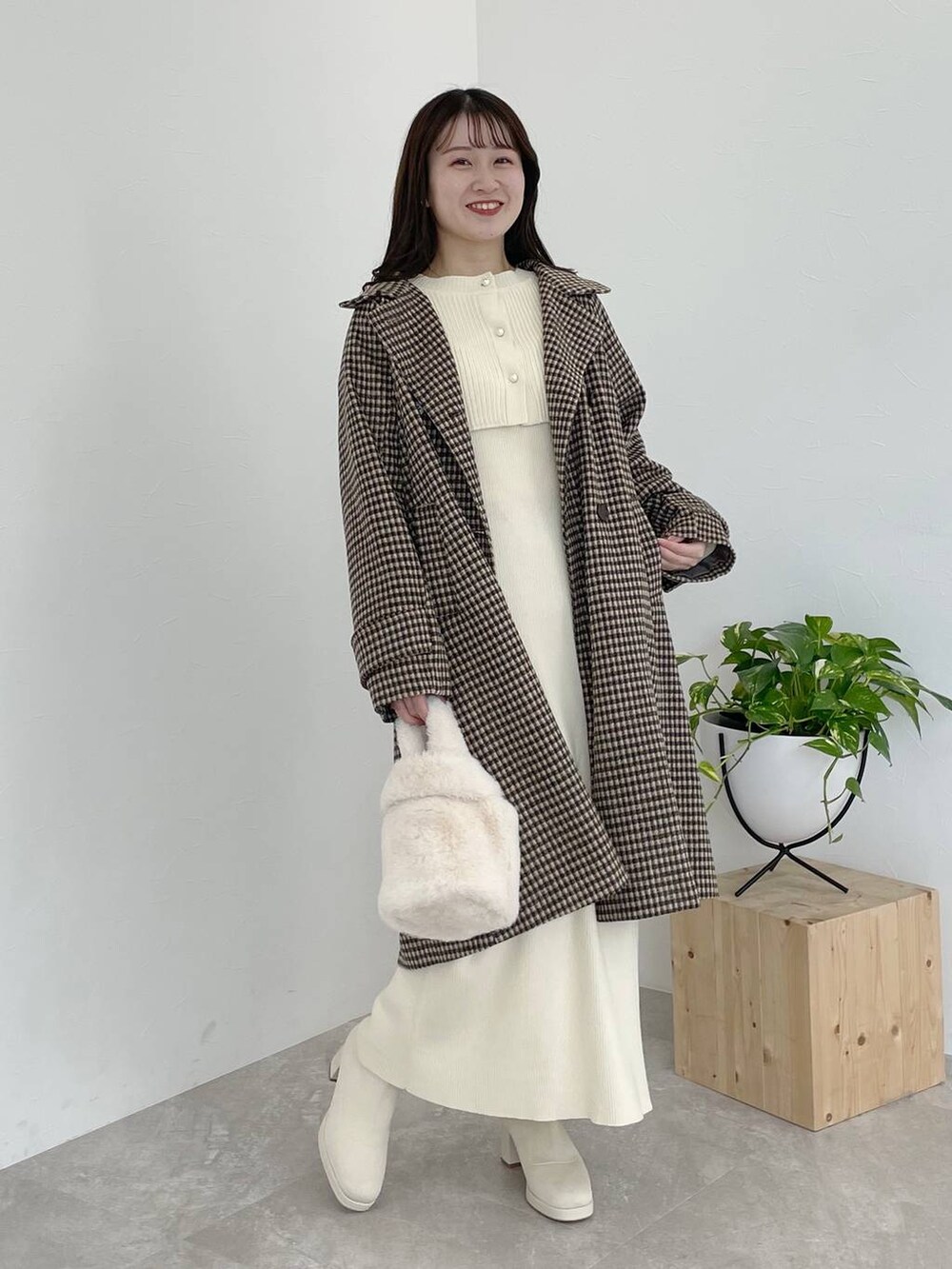 ホワイト系のブーツ、ホワイト系のハンドバッグ、ブラウン系のチェスターコートを着用したレディースの秋コーディネートの2枚目の写真