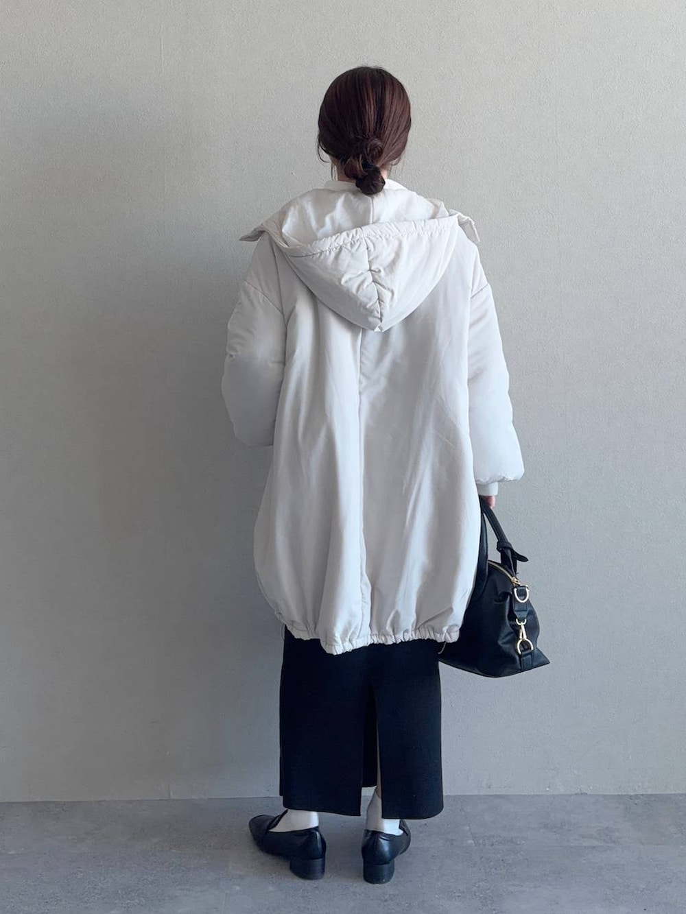 グレー系のニット/セーター、ブラック系のボストンバッグ、ブラック系のスカートを着用したレディースの冬コーディネートの2枚目の写真