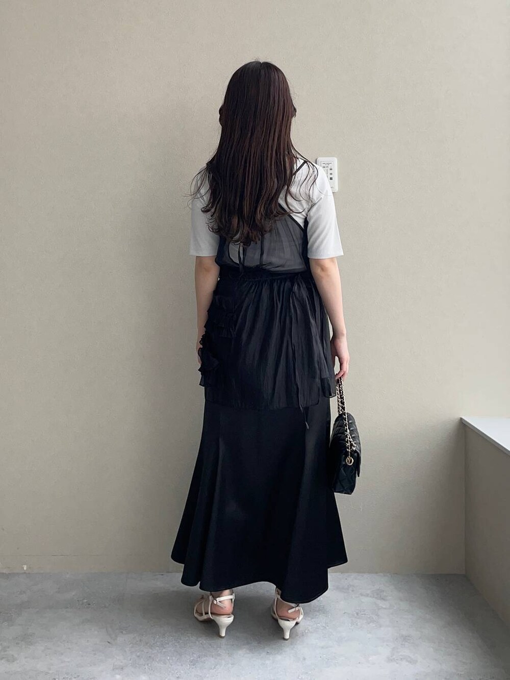 ブラック系のスカート、ブラック系のショルダーバッグ、ホワイト系のサンダルを着用したレディースの夏コーディネートの2枚目の写真