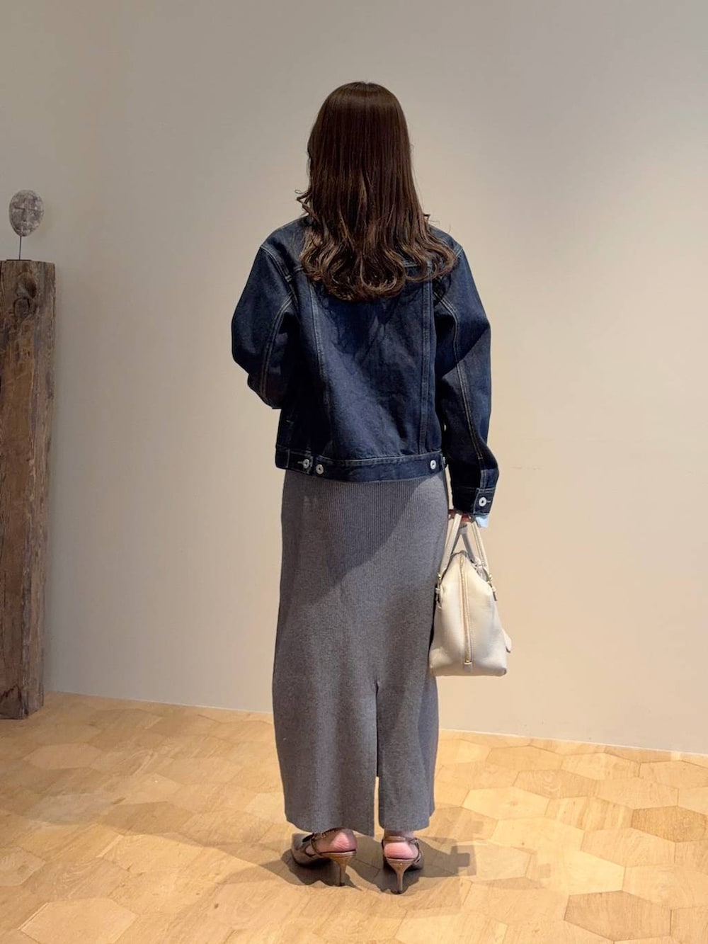 ベージュ系のハンドバッグ、グレー系のワンピース、ブルー系のデニムジャケットを着用したレディースの春コーディネートの2枚目の写真