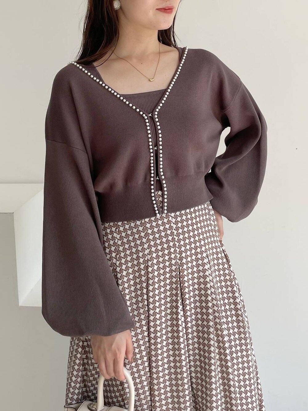 ホワイト系のハンドバッグ、ホワイト系のブーツ、ブラウン系のスカートを着用したレディースの夏コーディネートの3枚目の写真