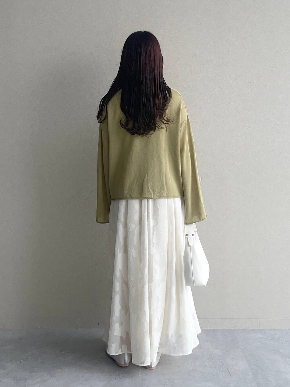 グリーン系のニット/セーター、シルバー系のバレエシューズ、ホワイト系のワンピースを着用したレディースの春コーディネートの2枚目の写真