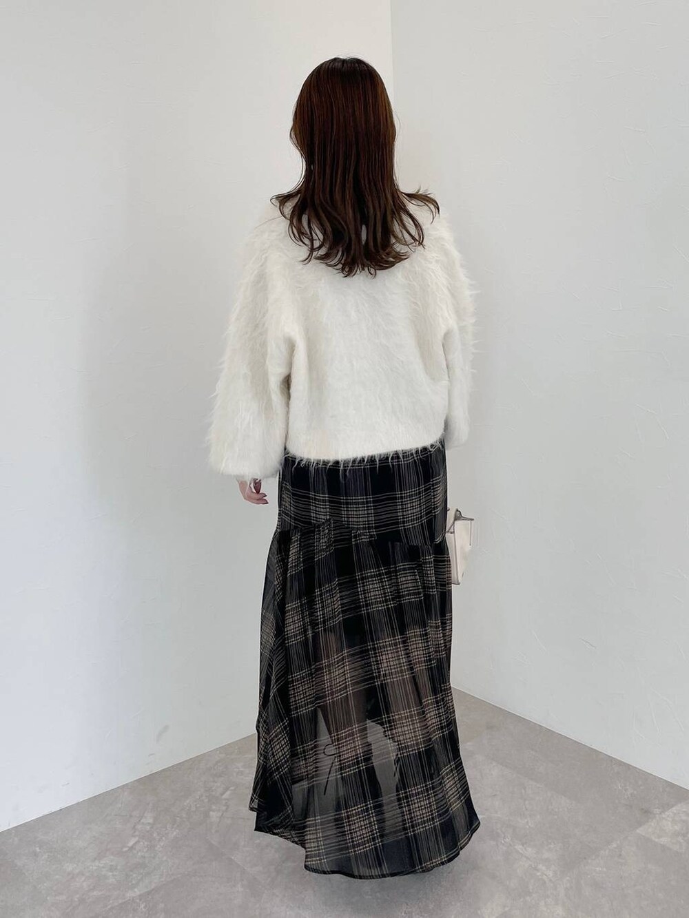 ホワイト系のカーディガン/ボレロ、ホワイト系のハンドバッグ、ブラック系のブーツを着用したレディースの秋コーディネートの2枚目の写真