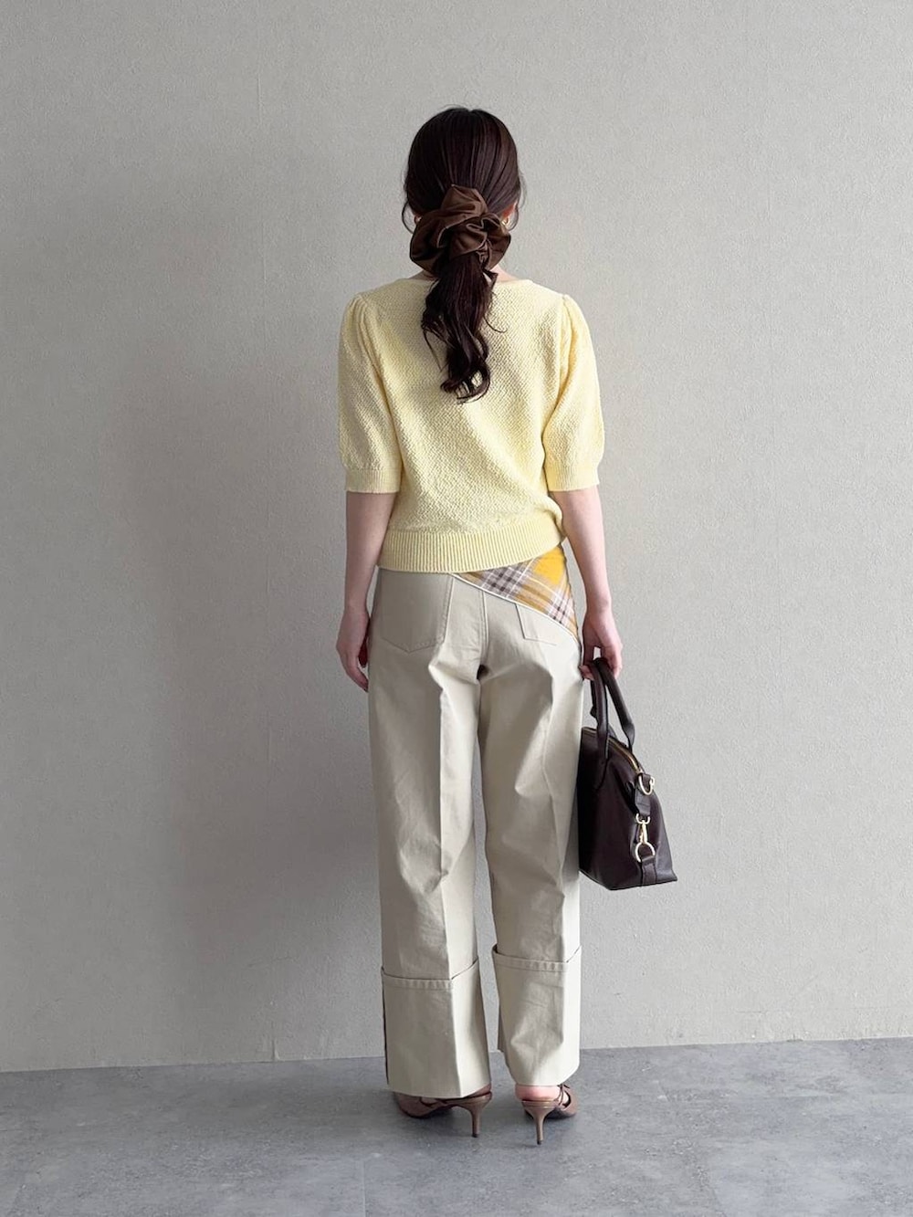 ブラウン系のボストンバッグ、イエロー系のカーディガン/ボレロ、ブラウン系のサンダルを着用したレディースの春コーディネートの2枚目の写真