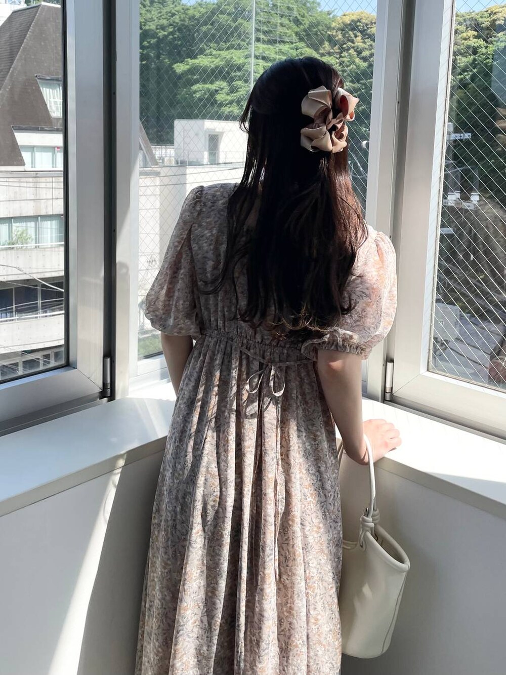 シルバー系のバレエシューズ、ホワイト系のハンドバッグ、ピンク系のワンピースを着用したレディースの夏コーディネートの5枚目の写真