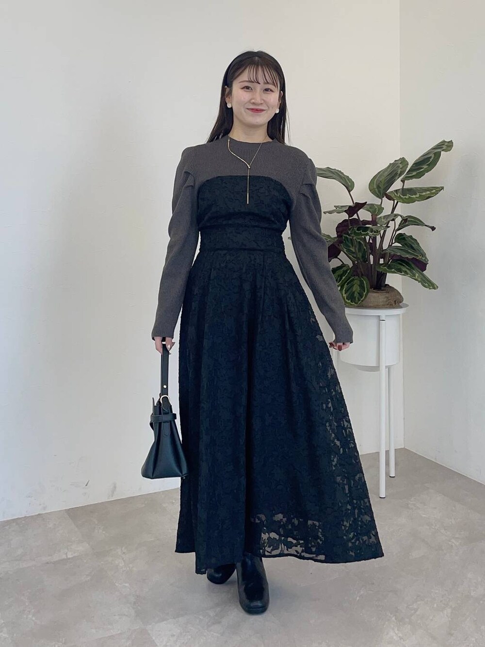 グレー系のノーカラーコート、ブラック系のショルダーバッグ、ブラック系のブーツを着用したレディースの冬コーディネートの3枚目の写真