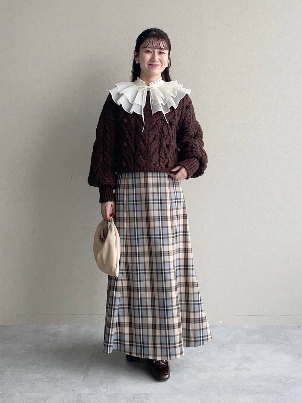 ベージュ系のハンドバッグ、ベージュ系のワンピースを着用したレディースの秋コーディネートの2枚目の写真