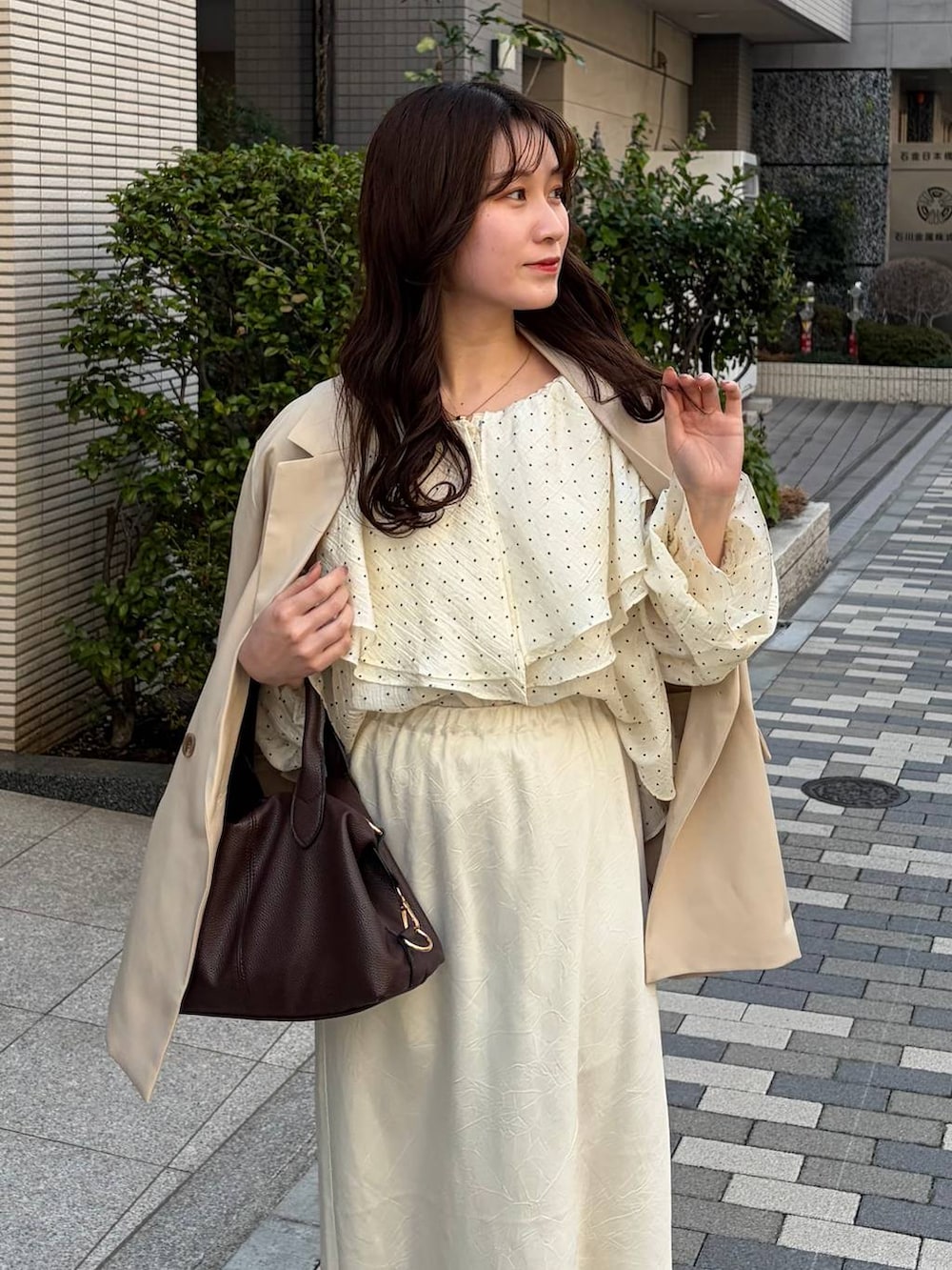 ホワイト系のスカート、ブラウン系のボストンバッグ、ベージュ系のテーラードジャケットを着用したレディースの春コーディネートの4枚目の写真