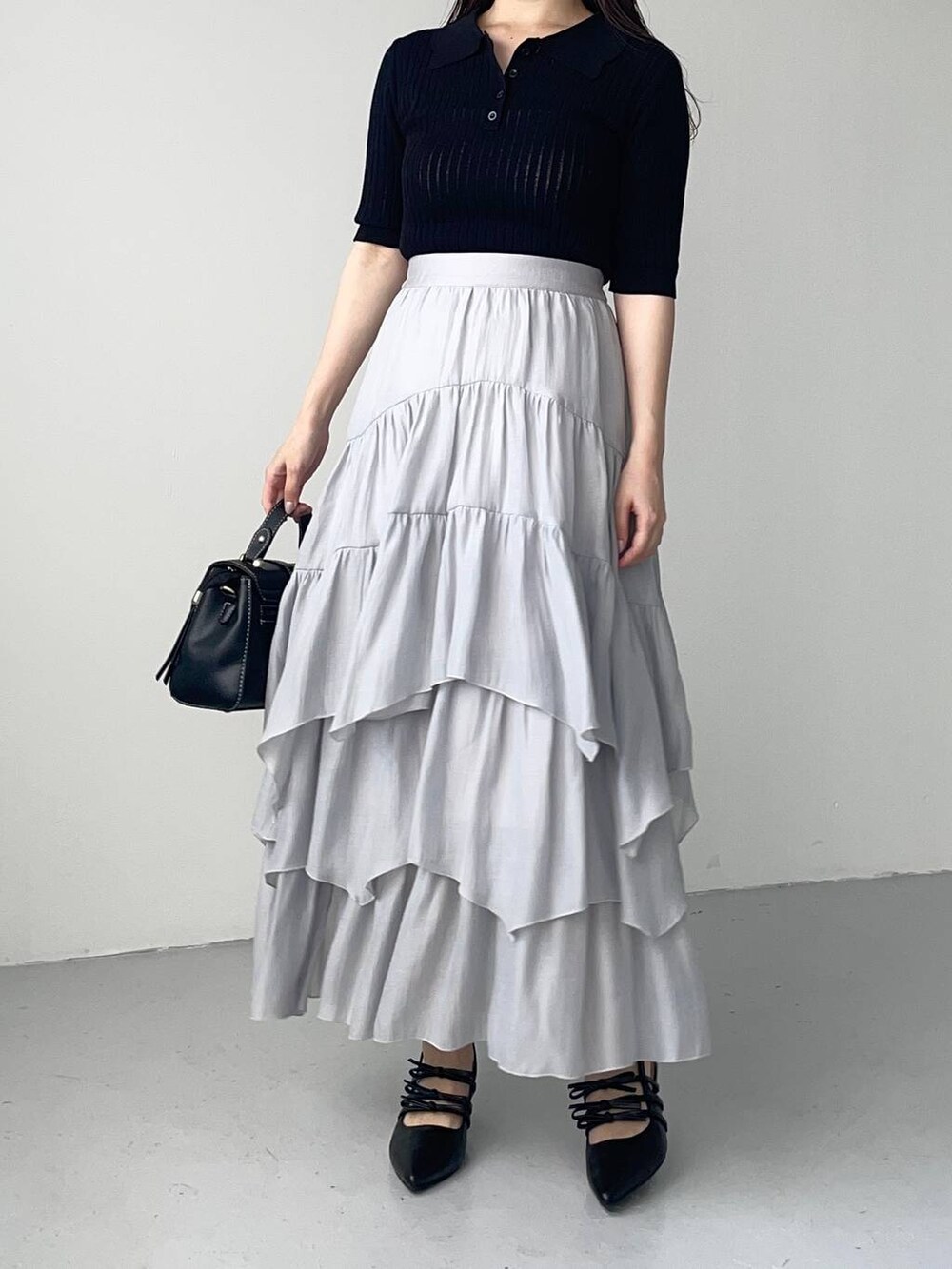 ブラック系のパンプス、ブラック系のショルダーバッグ、ブルー系のスカートを着用したレディースの夏コーディネートの3枚目の写真