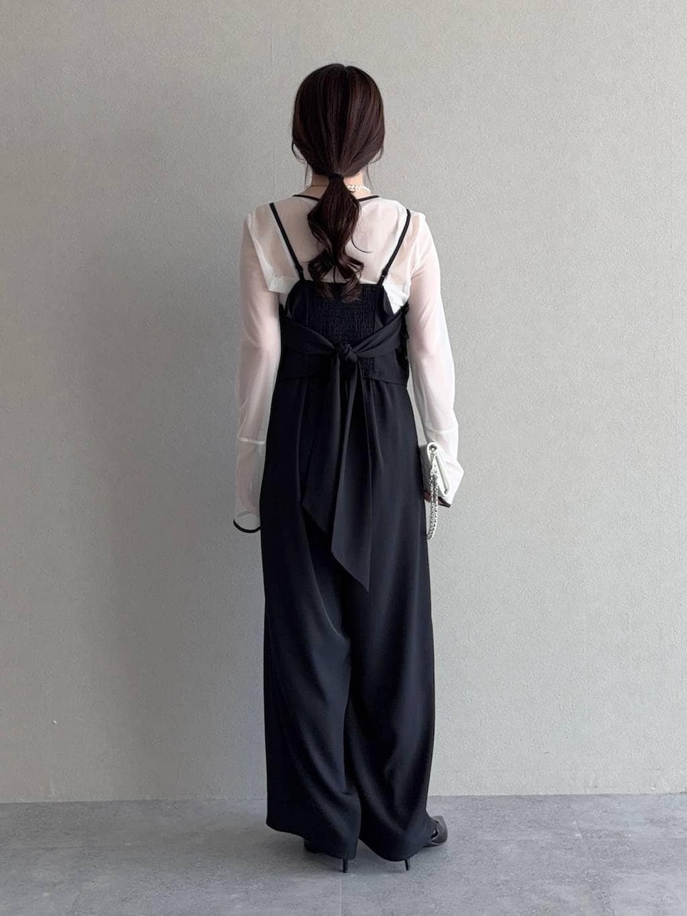 ブラック系のサンダル、ホワイト系のショルダーバッグ、ブラック系のパンツドレスを着用したレディースの春コーディネートの2枚目の写真