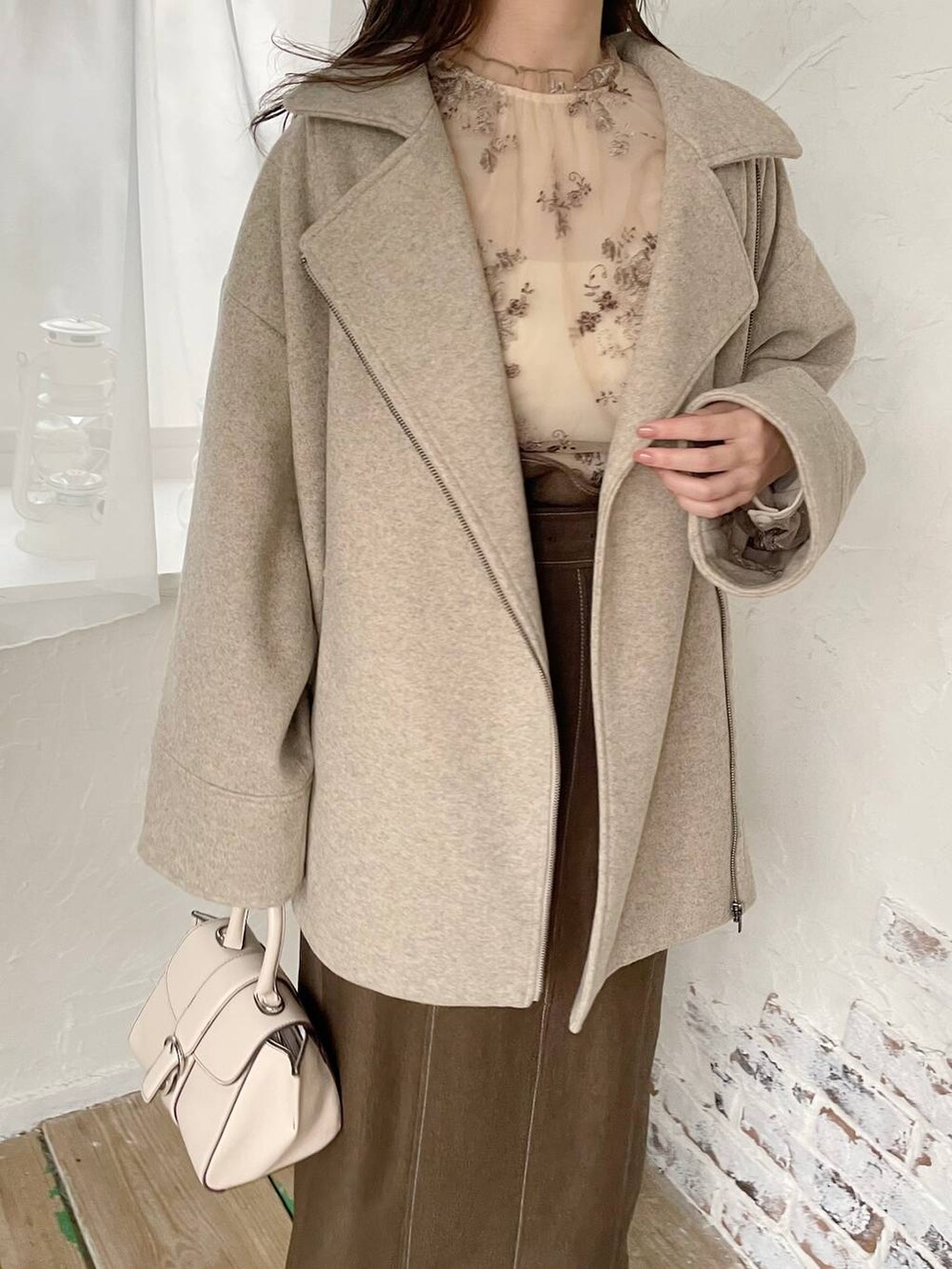 ホワイト系のハンドバッグ、ホワイト系のシャツ/ブラウス、ブラウン系のブーツを着用したレディースの秋コーディネートの3枚目の写真