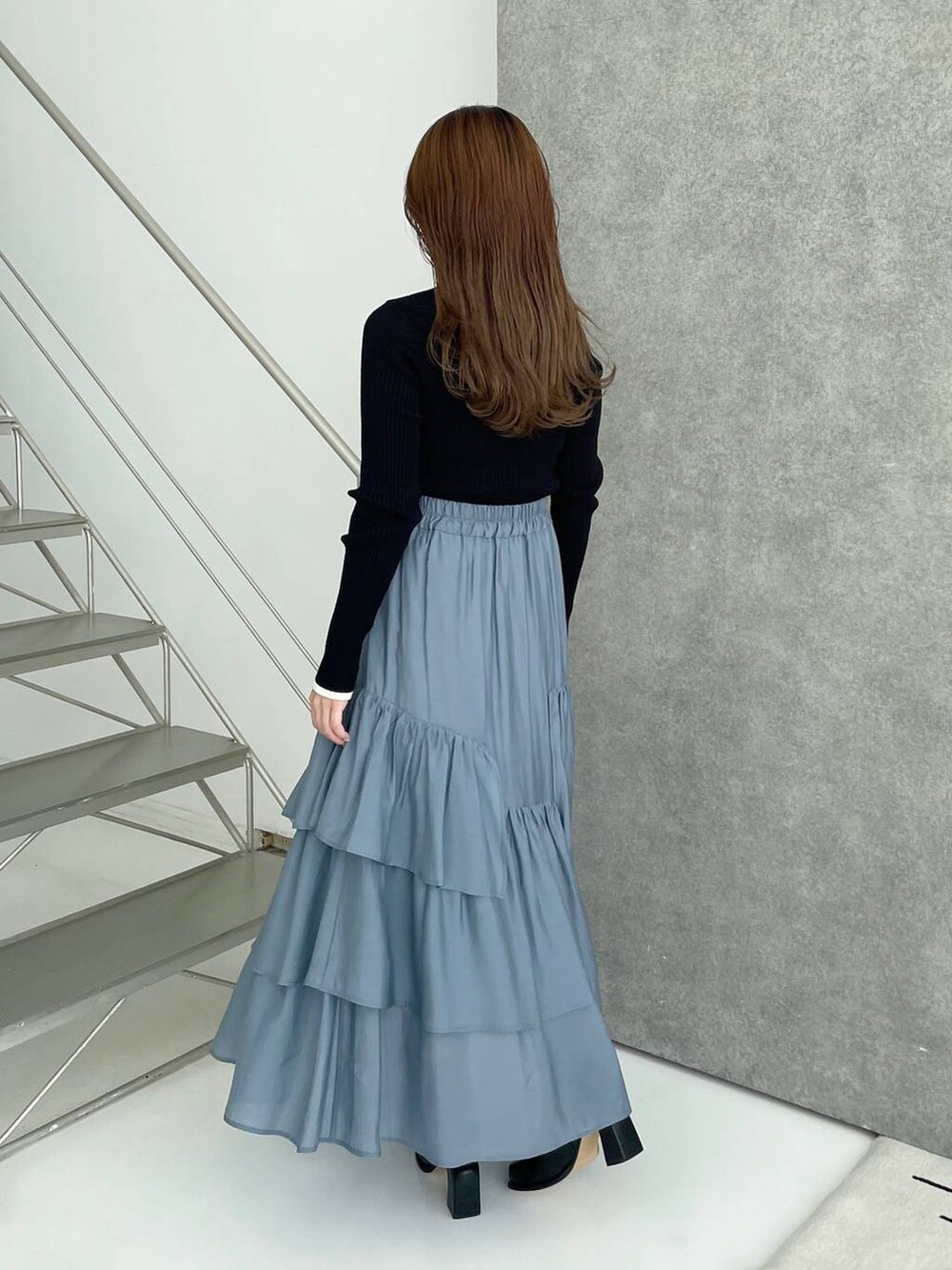 ブラック系のブーツ、ブラック系のニット/セーター、ブルー系のスカートを着用したレディースの秋コーディネートの2枚目の写真