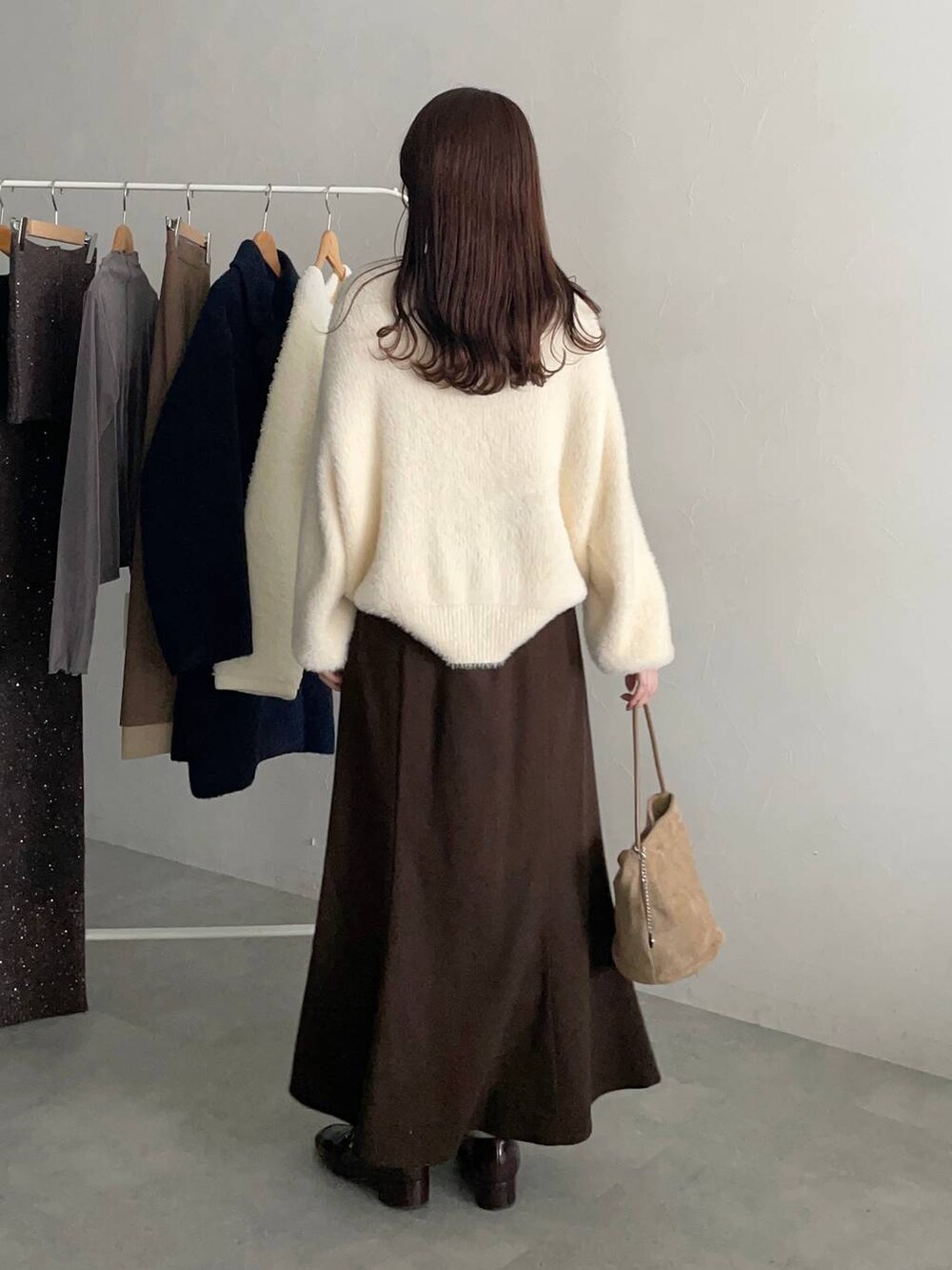 ベージュ系のハンドバッグ、ブラウン系のスカート、ホワイト系のニット/セーターを着用したレディースの秋コーディネートの2枚目の写真