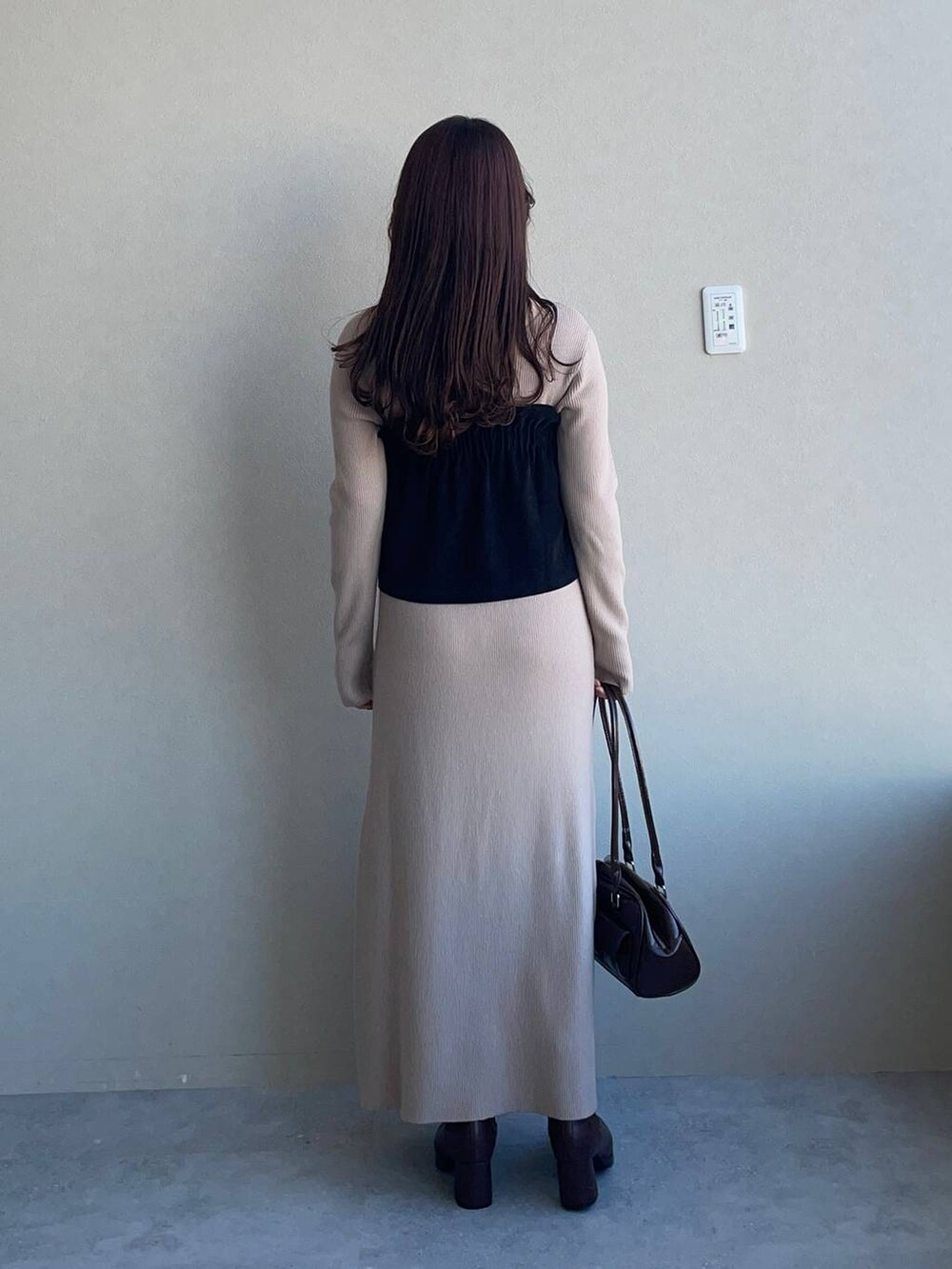 ブラウン系のブーツ、ブラウン系のハンドバッグ、ブラック系のスカートを着用したレディースの冬コーディネートの2枚目の写真