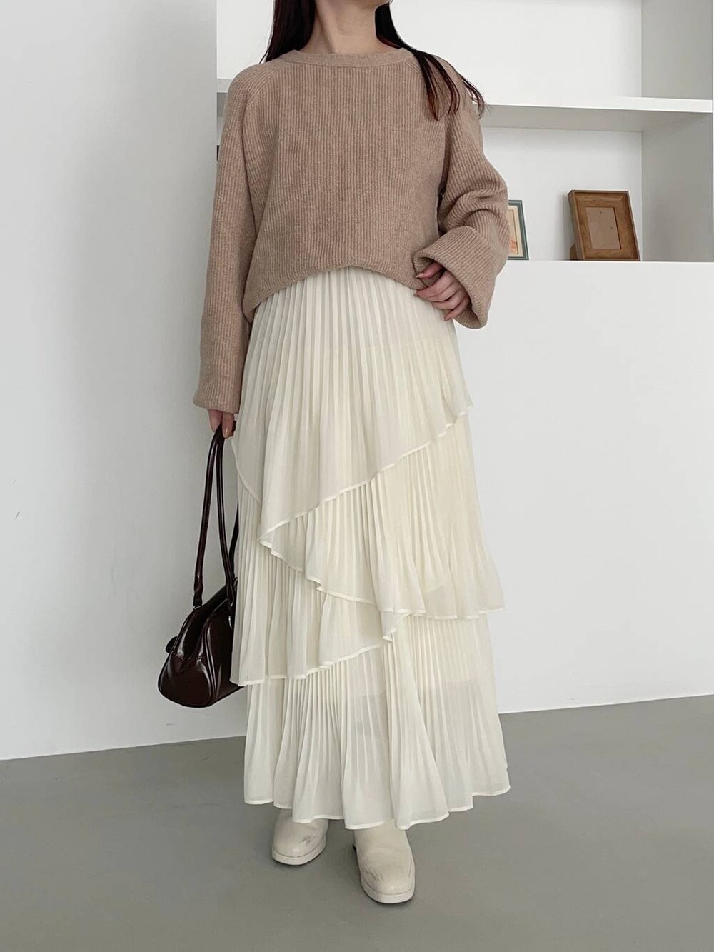 ホワイト系のブーツ、ベージュ系のニット/セーター、ブラウン系のハンドバッグを着用したレディースの冬コーディネートの3枚目の写真