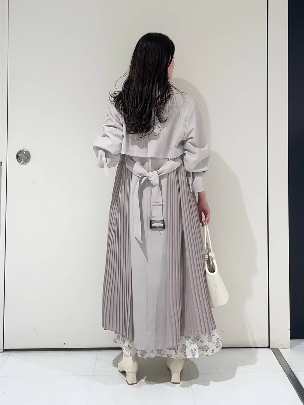 ブルー系のワンピース、ホワイト系のブーツ、グレー系のトレンチコートを着用したレディースの春コーディネートの2枚目の写真