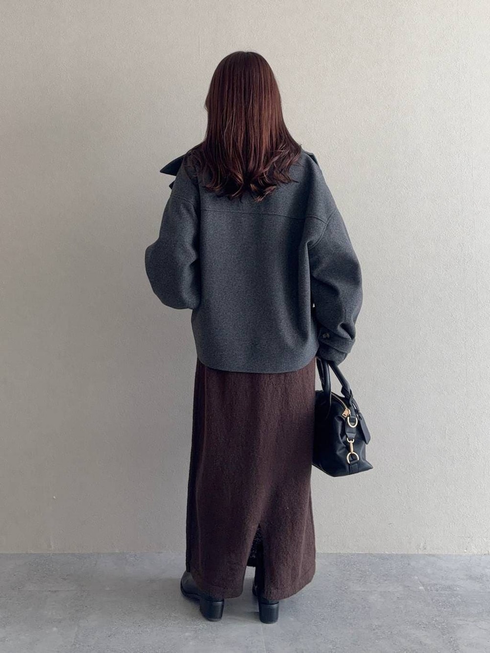 グレー系のピーコート、ブラック系のボストンバッグ、ブラック系のブーツを着用したレディースの冬コーディネートの2枚目の写真