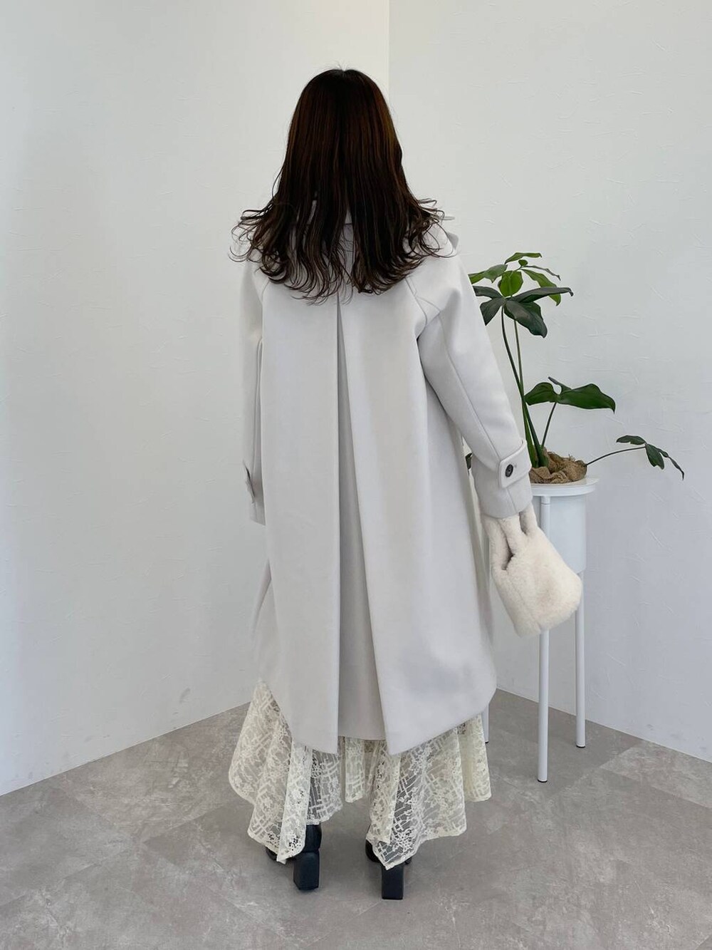 ホワイト系のチェスターコート、グレー系のブーツ、ホワイト系のスカートを着用したレディースの秋コーディネートの2枚目の写真