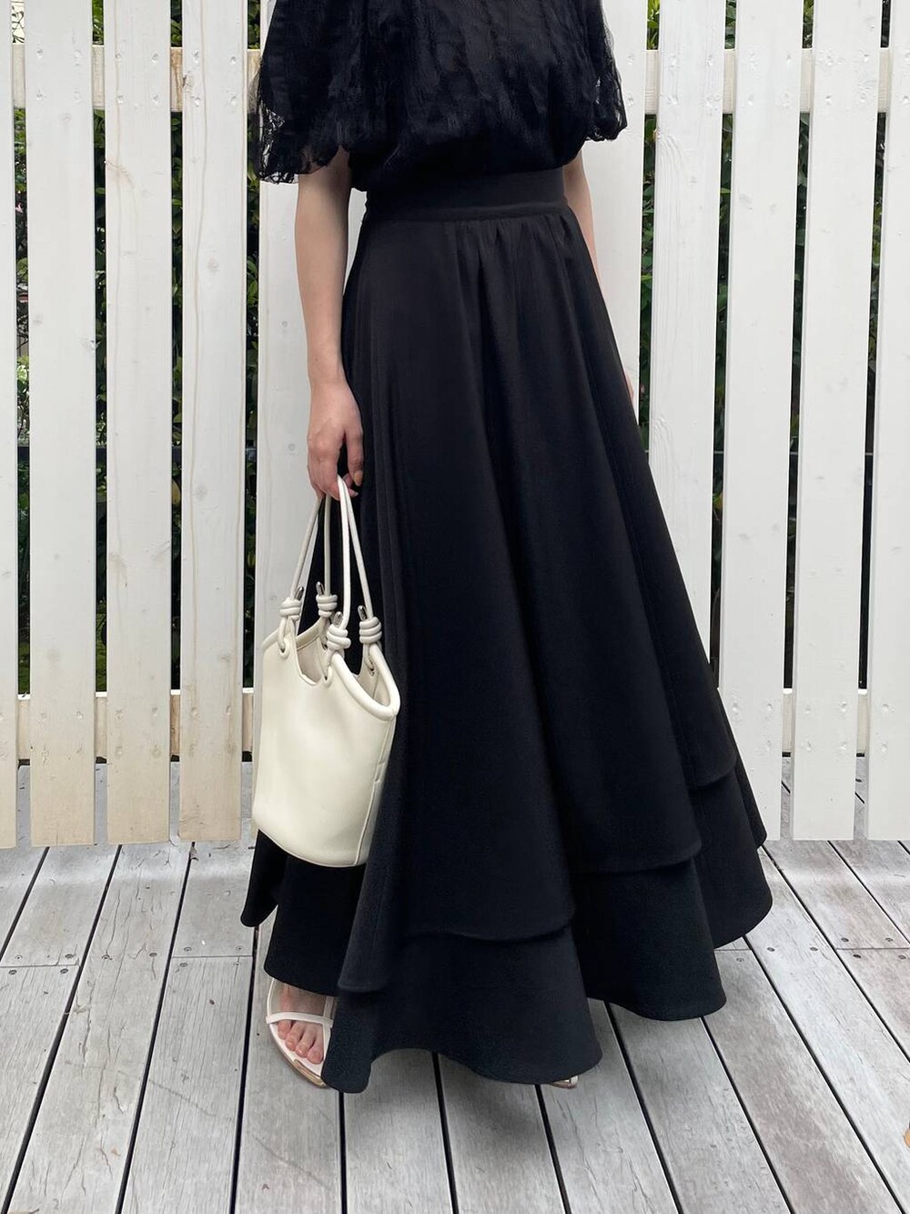 ホワイト系のハンドバッグ、ホワイト系のサンダル、ブラック系のシャツ/ブラウスを着用したレディースの夏コーディネートの4枚目の写真