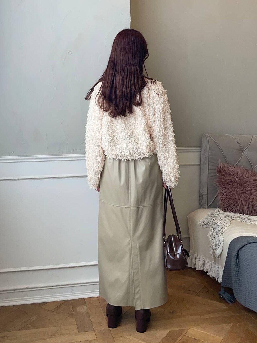 ブラウン系のブーツ、ベージュ系のスカート、ブラウン系のハンドバッグを着用したレディースの冬コーディネートの2枚目の写真