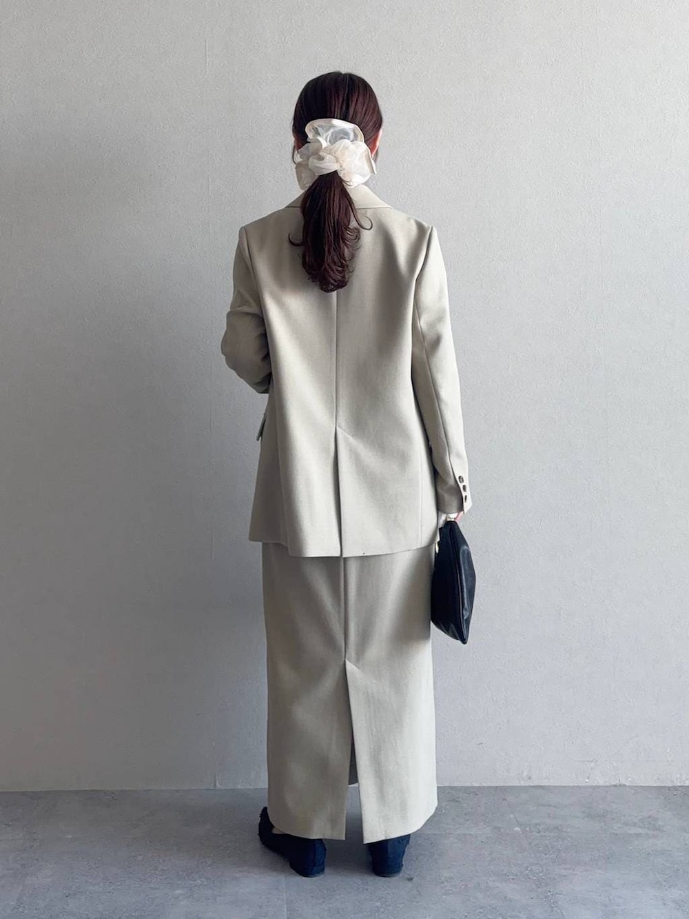 ブラック系のハンドバッグ、ベージュ系のテーラードジャケット、ベージュ系のスカートを着用したレディースの冬コーディネートの2枚目の写真