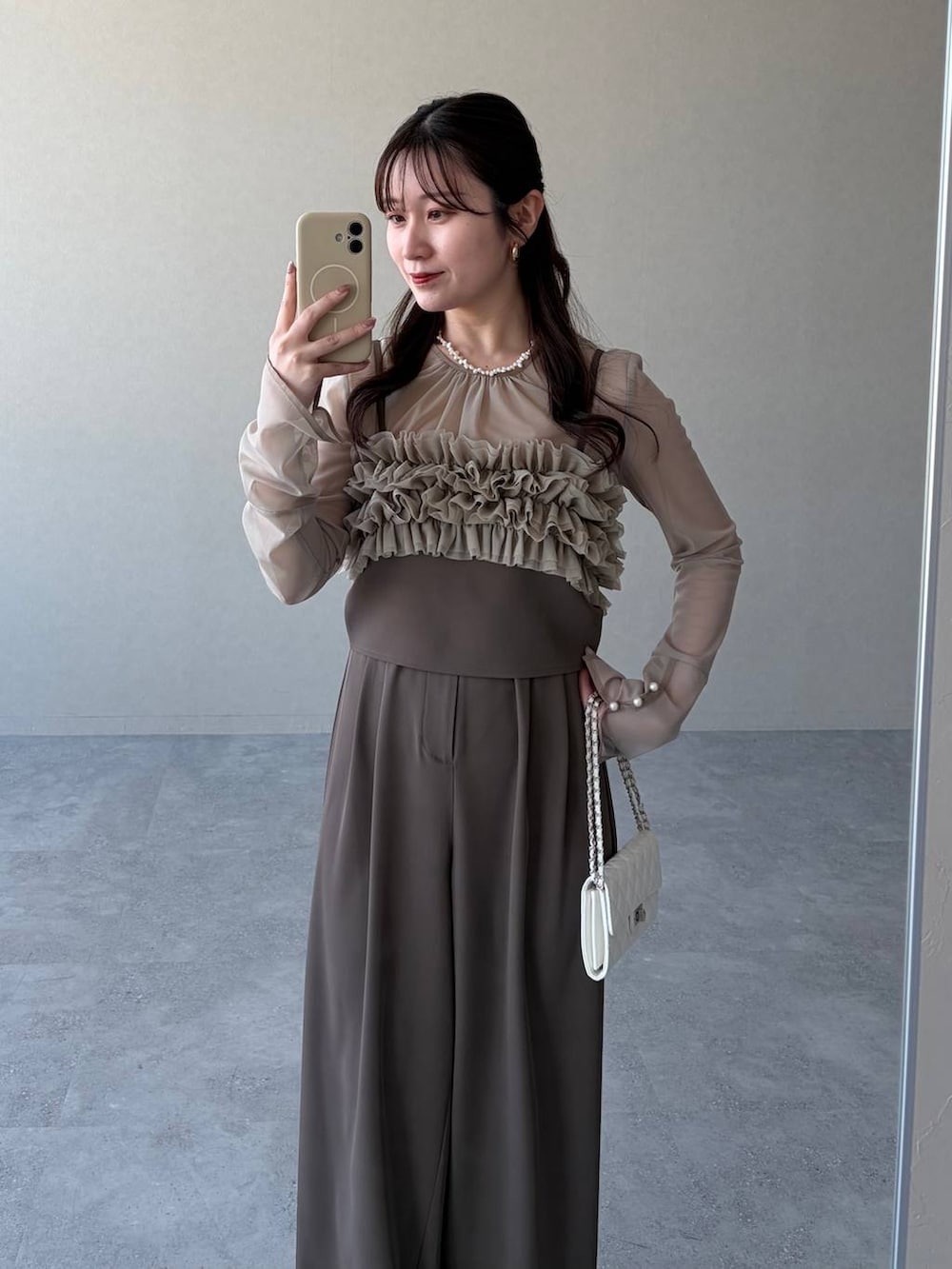 ブラウン系のサンダル、ホワイト系のショルダーバッグ、ベージュ系のパンツドレスを着用したレディースの春コーディネートの3枚目の写真