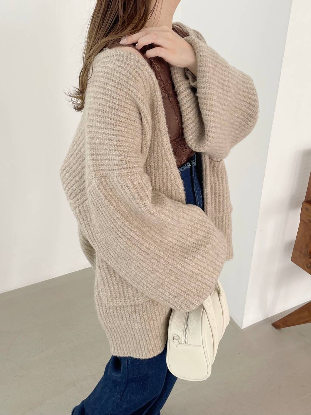 ブルー系のデニムパンツ、ホワイト系のボストンバッグ、ホワイト系のパンプスを着用したレディースの秋コーディネートの4枚目の写真