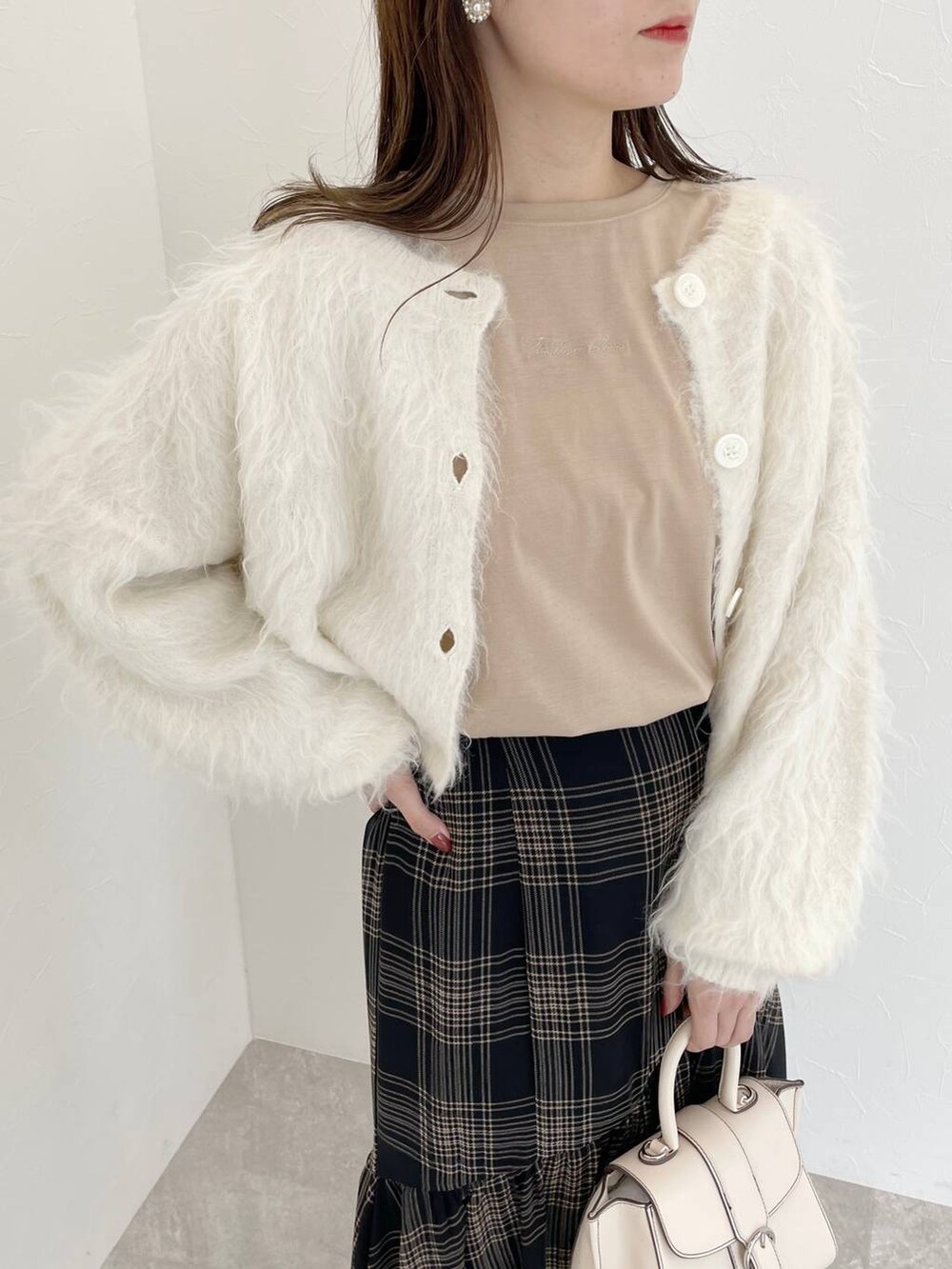 ホワイト系のカーディガン/ボレロ、ホワイト系のハンドバッグ、ブラック系のブーツを着用したレディースの秋コーディネートの3枚目の写真