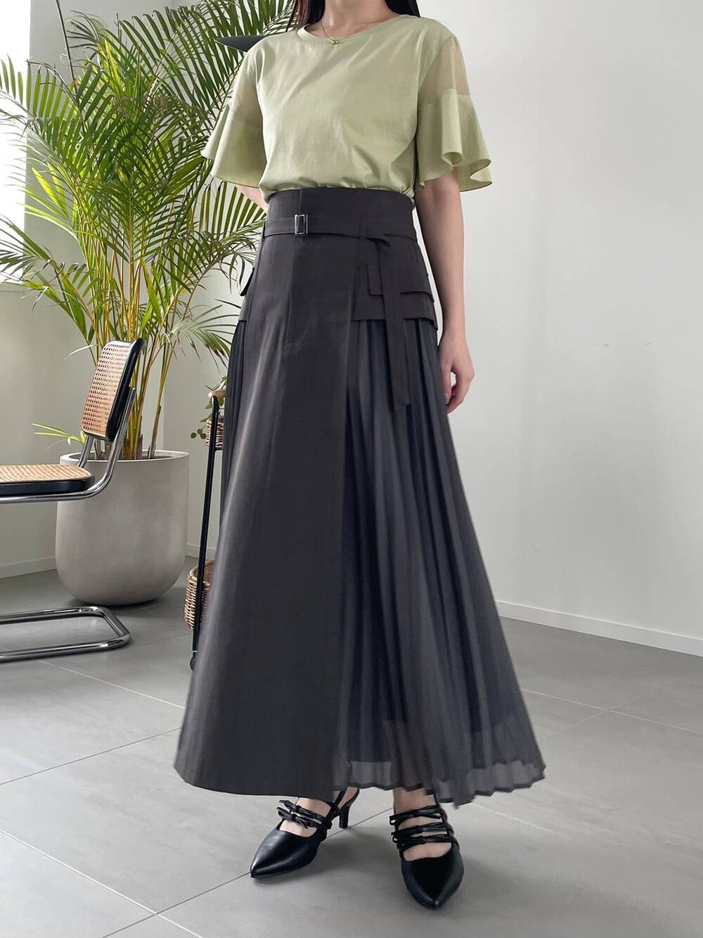 グレー系のスカート、グリーン系のTシャツ/カットソー、ブラック系のショルダーバッグを着用したレディースの春コーディネートの4枚目の写真