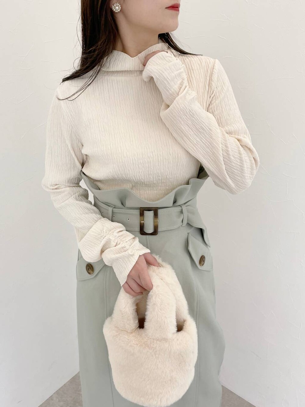 ホワイト系のブーツ、ホワイト系のハンドバッグ、グリーン系のスカートを着用したレディースの冬コーディネートの7枚目の写真