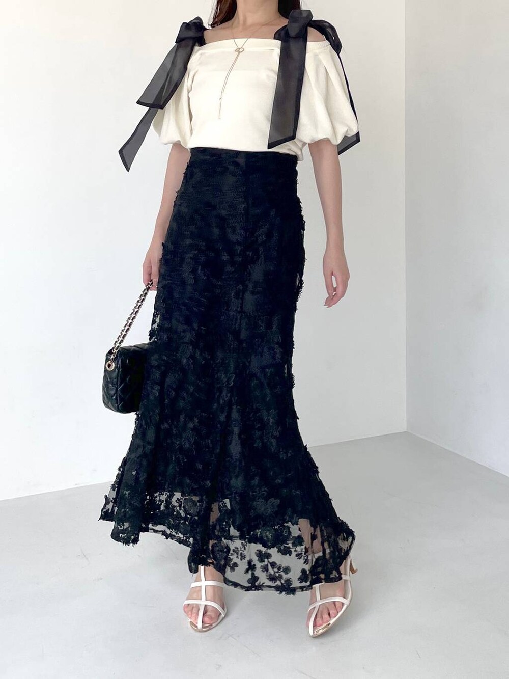 ホワイト系のニット/セーター、ブラック系のショルダーバッグ、ホワイト系のサンダルを着用したレディースの夏コーディネートの4枚目の写真