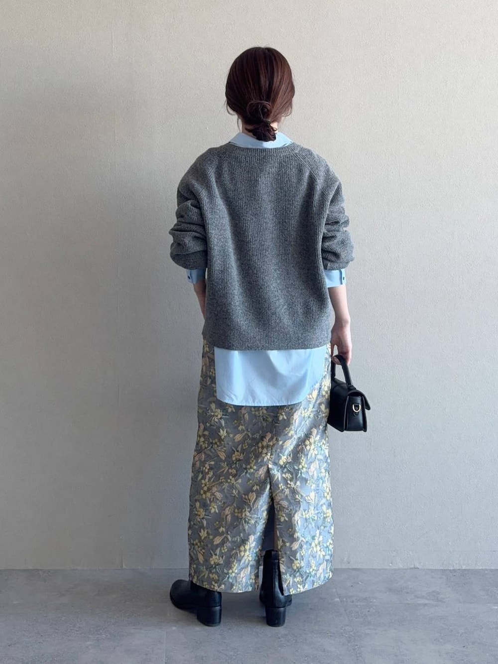 グレー系のニット/セーター、ブラック系のショルダーバッグ、ブラック系のブーツを着用したレディースの冬コーディネートの2枚目の写真