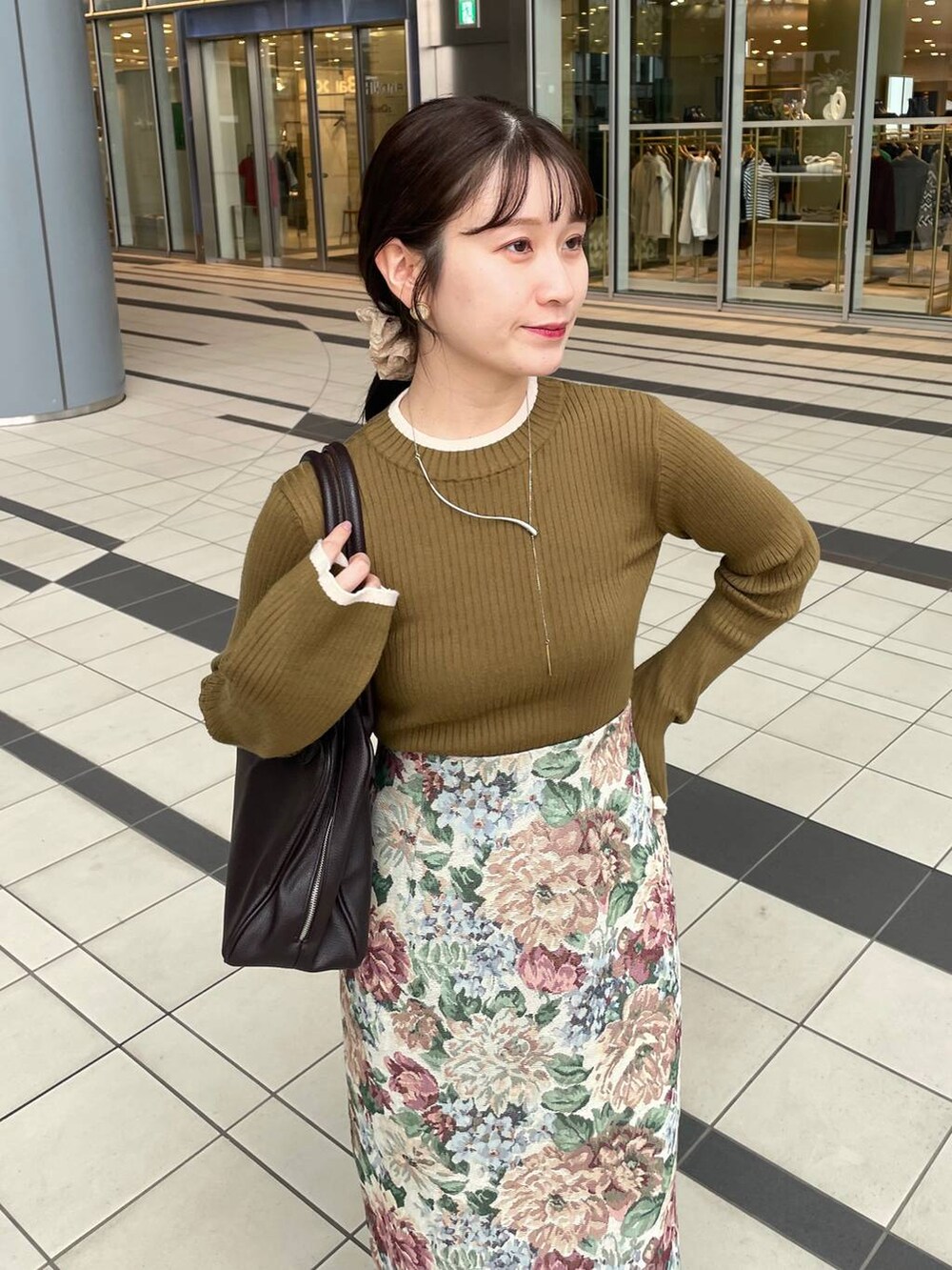 ブルー系のスカート、ブラウン系のトートバッグ、グリーン系のニット/セーターを着用したレディースの秋コーディネートの3枚目の写真